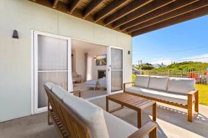 a patio with a couch and a table at Sea Sand and Serenity at Stockton - Stunning Sophistication in Stockton