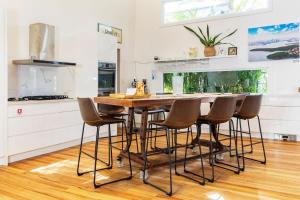 a kitchen with a wooden table and bar stools at The Lake Palace in Murrays Beach +53 photos
