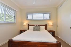 a bedroom with a bed with two lamps and two windows at Wangi Lakehouse in Wangi Wangi