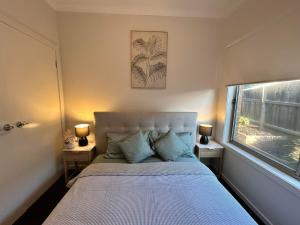 a bedroom with a bed with blue pillows and a window at NatureWalkBrookfield in Melton South