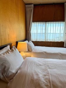 a bedroom with two beds and a lamp and a window at Shell Beach Hamanako - Vacation STAY 14730 in Hamamatsu