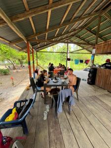 a group of people sitting at a table on a deck at Cabaña Vikana in Nuquí