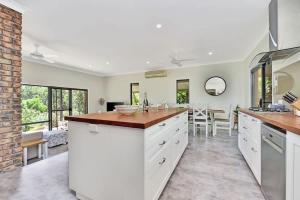 a kitchen with white cabinets and a dining room at Kookaburra Range in Greta