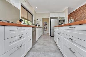a kitchen with white cabinets and a brick wall at Kookaburra Range in Greta