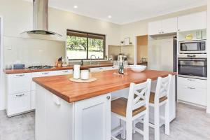 a kitchen with white cabinets and a wooden counter top at Kookaburra Range in Greta