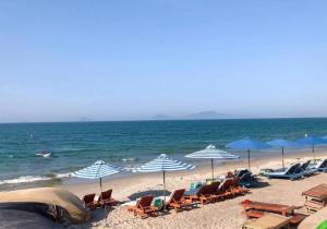 a beach with chairs and umbrellas and the ocean at Hoi An Ocean Waves Homestay in Hà My Tây (2) +6 photos