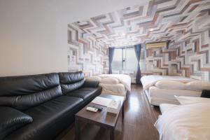 a living room with a leather couch and a geometric wall at R Hotel - Vacation STAY 19198 in Chiba