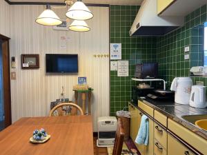 a kitchen with green tiled walls and a wooden table at Kohaku - Vacation STAY 20481 in Nagahama