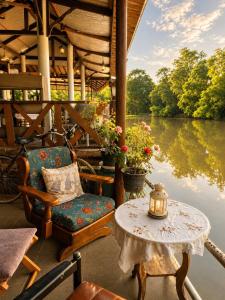 a porch with a table and a chair and water at The Scarecrow House in Ban Doem Bang (1)