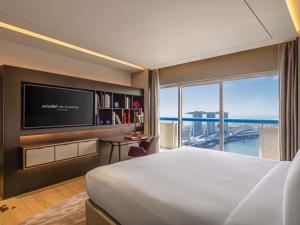 a hotel room with a bed and a television at Swissotel The Stamford Singapore in Singapore