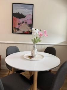 a white table with a vase of flowers on it at Fitzroy Cottage one bedroom CBD accommodation in Tamworth