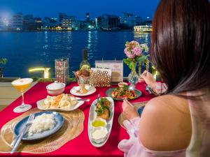 a woman sitting at a table with plates of food at Amdaeng Bangkok Riverside Hotel in Bangkok