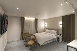 a hotel room with a bed and a table and chairs at 주노 호텔 in Tujŏng-dong