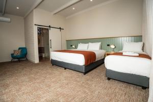 a hotel room with two beds and a chair at The Clovercrest Hotel Motel in Modbury