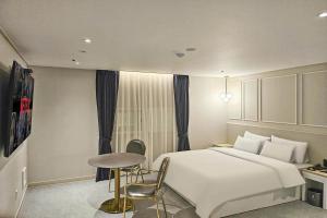 a bedroom with a large white bed and a table at 주노 호텔 in Tujŏng-dong