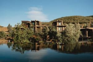 a house on a hill next to a body of water at o2 Resort Valle de Guadalupe in Valle de Guadalupe