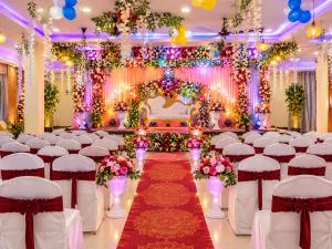 a wedding banquet hall with white chairs and a altar at hotel wisdom celebration in Motīhāri