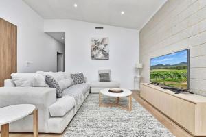 a living room with a couch and a flat screen tv at Somerville Wines Lux Escape 3-Bedroom Cottage Near Broke Wineries in Broke