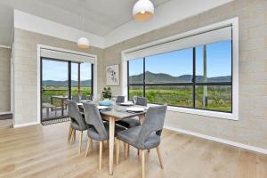 a dining room with a table and chairs and a large window at Somerville Wines Lux Escape 3-Bedroom Cottage Near Broke Wineries in Broke