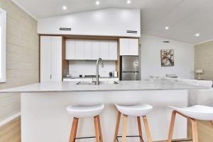 a kitchen with a large white counter and stools at Somerville Wines Lux Escape 3-Bedroom Cottage Near Broke Wineries in Broke +12 photos