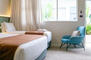 a hotel room with two beds and a blue chair at The Clovercrest Hotel Motel in Modbury +5 photos