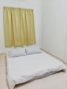 a bed in a room with a yellow curtain at Chendering Beach Stay in Kuala Terengganu
