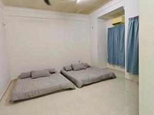 a bed in a white room with blue curtains at Chendering Beach Stay in Kuala Terengganu