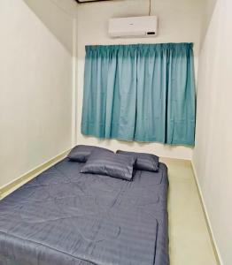 a bed in a small room with a blue curtain at Chendering Beach Stay in Kuala Terengganu