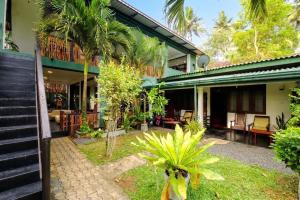 a house with a courtyard with palm trees at Surf Dine in Matara