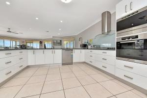 a large white kitchen with white cabinets and appliances at Noble Willow Homestead in Lovedale +39 photos