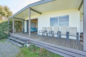 a house with a wooden deck with chairs on it at Far View - Pets, Linen, Wi-Fi, Netflix, Caravan, EV in Venus Bay