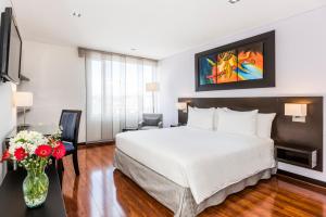 a hotel room with a bed and a vase of flowers at One Sixteen Hotel in Bogotá