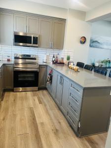 a kitchen with stainless steel appliances and wooden floors at Southside Haven Edmonton in Edmonton