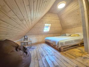 a bedroom with a bed in a wooden room at Bat's Cave Hut Transylvania - Rustic Retreat in Sub Piatra
