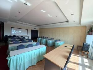 a conference room with blue chairs and tables and a screen at Kudat Ria Hotel Plt in Kudat