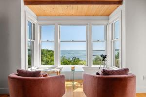 a living room with two chairs and a table and windows at Vista Mare in Rockport