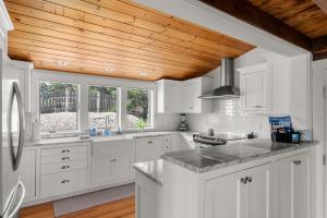 a kitchen with white cabinets and a wooden ceiling at Vista Mare in Rockport +23 photos