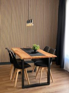 a wooden table with black chairs and a wooden wall at Demhouse in Gössenheim