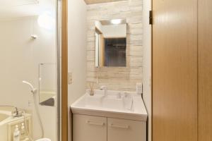 a white bathroom with a sink and a mirror at Green hills 102 in Kumamoto