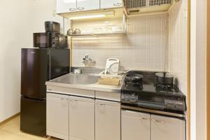 a kitchen with a sink and a black refrigerator at Green hills 102 in Kumamoto