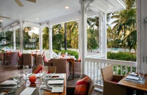 un restaurante con mesas, sillas y palmeras en Tranquility Bay Resort, en Marathon