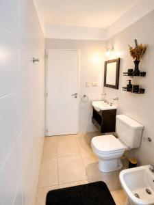 a white bathroom with a toilet and a sink at Bohemian dream in Ezeiza +16 photos