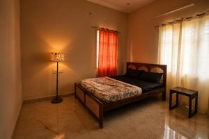 a bedroom with a bed and a lamp and a window at Holapu Thayi Villa in Mysore