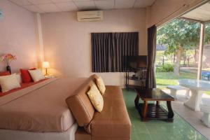 a bedroom with a bed and a couch and a tv at The Scarecrow House in Ban Doem Bang (1)