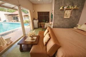a living room with a couch and a table and a pool at The Scarecrow House in Ban Doem Bang (1)