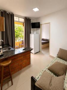 a kitchen and living room with a couch and a refrigerator at Casa Da Praia Apart Hotel in Florianópolis
