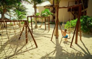 a young child playing on a swing set on the beach at La Zebra a Colibri Boutique Hotel in Tulum