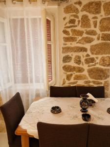 a dining room table with chairs and a stone wall at Mikel's Village House in Káto Garoúna