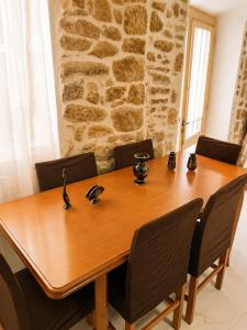 a wooden table with chairs and a stone wall at Mikel's Village House in Káto Garoúna +5 photos