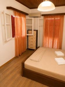a bedroom with a large bed with an orange curtain at Mikel's Village House in Káto Garoúna